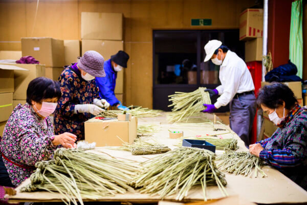 この貴重な青い藁を扱うには、機械では再現できない熟練の技が必要です。お正月飾りは歳神様に宿っ ていただく為のものですので、清らかで美しく、力強くなくてはならないと私達は信じています。だか らこそ、日本の文化を守りながらも、ひとつひとつ真心を込めて手作りすることにこだわっているので す。